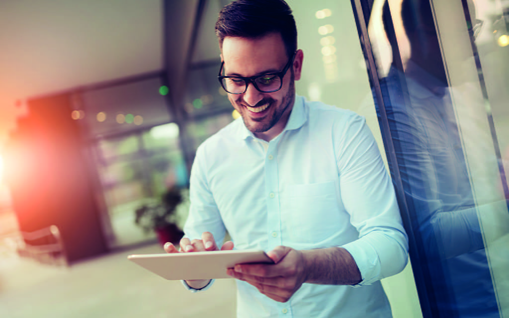 Junger Mann ist an einem Tablet online Junger Mann ist an einem Tablet online